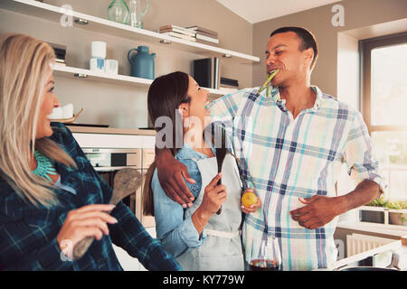 Fröhliche Freunde, etwas Spaß an der Küche beim Kochen. Mann zeigt Walross Stoßzähne mit Spargel Sticks. Stockfoto