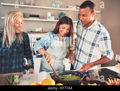 Happy multirassischen Freunde braten Spargel auf der Pfanne. Stockfoto