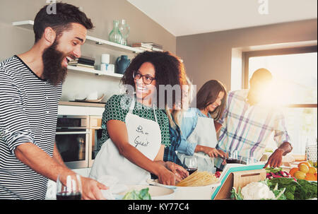 Lachend Gruppe junger Studenten Kochen in der Küche mit hellem Sonnenlicht gießen durch das Fenster Stockfoto