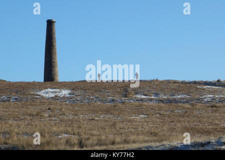 Zwei Wanderer zu Fuß zu den Rochen Mühle Schornstein an Grassington alten stillgelegten Minen auf Grassington Moor, Wharfedale, Yorkshire Dales National Park, Stockfoto