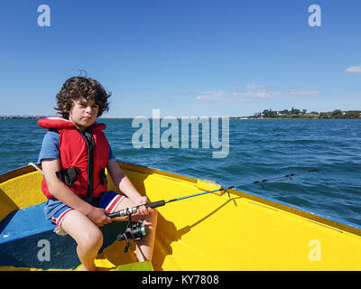 Smart phone Bild Kid, um die Fischerei mit kleinen Beiboot auf Tauranga Hafen in hellem Gelb Beiboot. Stockfoto