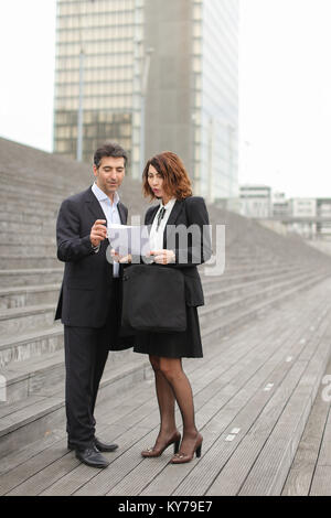 Layer und Client stehen auf große graue Treppe. Frau, die Dokumente über Gericht Erklärung in der Hand. Menschen erzählen über sehr gute Ende der Rechtsstreitigkeiten und bout Stockfoto