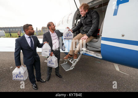 Brüder Faz (Mitte) und Jaf Ahmed von der Akash Restaurant in Fareham, Hampshire, helfen Sie, James Emery (rechts) laden ein Curry Gerichte zum Mitnehmen auf eine Ebene im Solent Flughafen, Lee-On-The-Solent, so dass es nach Frankreich für die Britische ex-Pat und seinen Freunden am Saucats Airfield, südlich von Bordeaux geflogen werden kann. Stockfoto