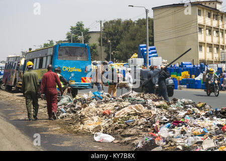 Einen großen Haufen von plastik Müll und anderen Abfällen sitzt in der Mitte der Straße als Menschen und Fahrzeuge Vergangenheit gehen, Nairobi, Kenia, Ostafrika Stockfoto