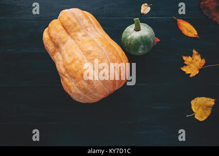 Kürbisse mit gelben Blätter fallen auf dunklem Hintergrund Herbst saisonal Konzept Symbol von Halloween Urlaub top View Stockfoto
