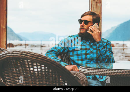 Bärtiger Mann sprechen von Smartphone modernen Lifestyle erfolg Technologie Konzept Geschäftsmann sitzt in der Nähe der Fenster Stockfoto