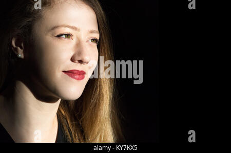 Porträt einer blonden jungen Frau weg in eine selbstbewusste Weise suchen, closeup headshot, schwarzer Hintergrund, natürliches Licht, im Innenbereich. Stockfoto