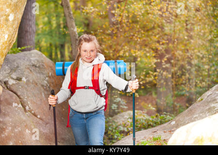 Portrait von jugendlichen Mädchen mit Rucksack und Trekking Stöcke zu Fuß durch einen Berg im Herbst Stockfoto