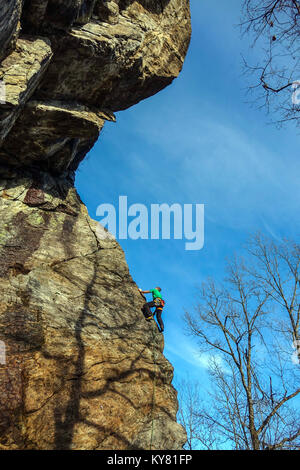 Männliche Kletterer auf steilen Granit Felsen mit rotem Rock und blauer Himmel Stockfoto