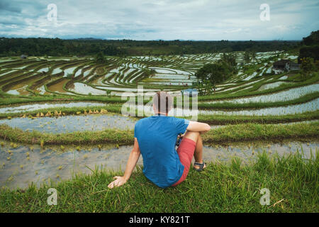 Junger Mann Reisender Sitzen und Entspannen im Freien am Reis Felder auf Bali Indonesien angebaut. Stockfoto