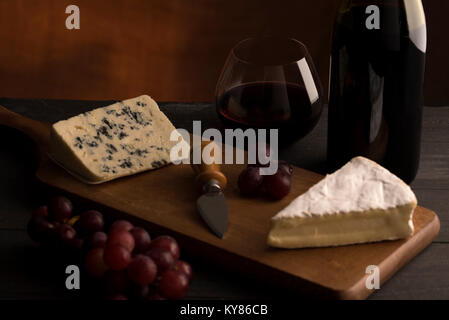 Rotwein in stemless Glas mit Wein Flasche roten Trauben und Käse Stockfoto