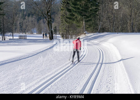 Gespurte Loipen zum Langlaufen mit Langläufer in roter Jacke im Winter sonnige Tag in den Bergen Stockfoto