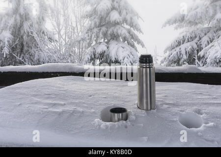 Eine Thermoskanne mit heißem Tee auf einem schneebedeckten Tabelle. Das Konzept des Überlebens, Sicherheit in den Bergen Stockfoto