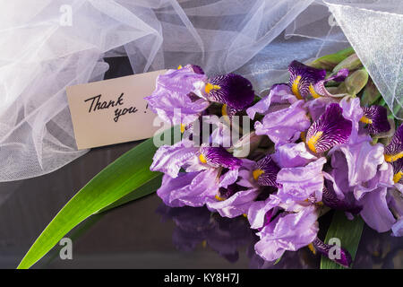 Zusammensetzung der Blumenstrauß aus irisen und weissen Schleier auf einem dunklen reflektierenden Hintergrund mit Karte Danke Stockfoto