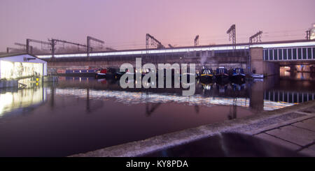 Ein Zug nähert sich der London St Pancras railway station auf einem Viadukt über das Regent's Canal auf eine stimmungsvolle neblige Nacht, mit langen Exposition motion Stockfoto