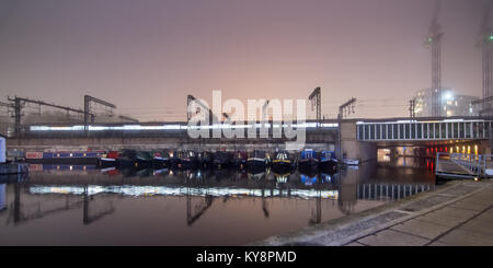 Ein Zug nähert sich der London St Pancras railway station auf einem Viadukt über das Regent's Canal auf eine stimmungsvolle neblige Nacht, mit langen Exposition motion Stockfoto