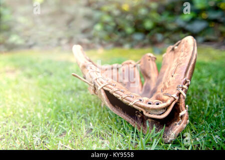 Alte abgenutzte beliebte Baseball Handschuh im Gras liegend nach dem Spiel an einem warmen Sommertag Stockfoto