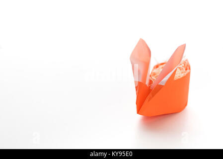 Eine bunte orange origami Ostern Bunny Hase aus Papier mit Stroh gefüllt, bereit für Ei für Ostern, auf weißem Hintergrund Stockfoto