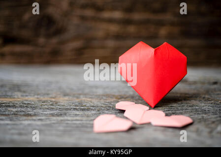 Horizontale Sammlung verschiedener Größen von origami Papier Herzen zum Valentinstag Schuß gegen rustikale Scheune Holz Hintergrund Stockfoto