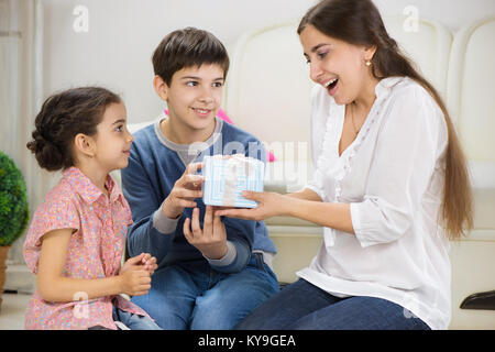 Süße Kinder präsentieren ein Geschenk Mutter Stockfoto