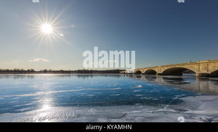 Eis und Sonne Licht auf dem Potomac River, nachdem es während der winterlichen Kälte blast mit der Memorial Bridge Virginia anschließen in der Ferne zu DC erstarrte. Stockfoto