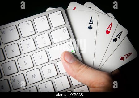 Eine Tastatur und vier Asse in der Hand. Stockfoto