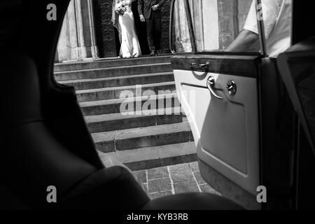 Die Braut und der Bräutigam gehen von Kirche zu wagen. Stockfoto