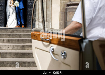 Die Braut und der Bräutigam gehen von Kirche zu wagen. Stockfoto