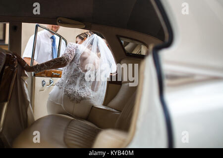 Die Braut und der Bräutigam gehen von Kirche zu wagen. Stockfoto