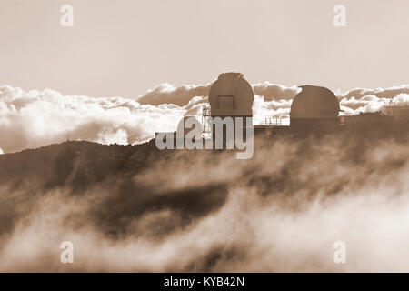 Blick auf die Observatorien auf der Oberseite des Haleakala auf Maui, Hawaii im zwischen den Wolken. Stockfoto