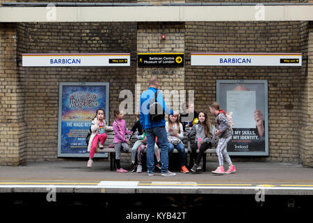 Gruppe von Mädchen mit einem Elternteil auf einen Tag warten, bis ein Zug auf dem Barbican Station u-Plattform im Herbst in London England UK KATHY DEWITT Stockfoto