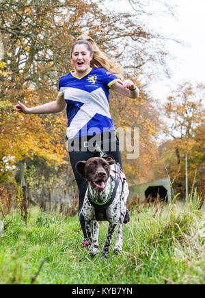 Hunde und Läufer konkurrieren in CaniCross Stockfoto