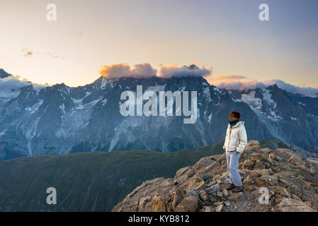 Frau beobachten, atemberaubenden Sonnenaufgang über Täler, Grate und Gipfel. Mont Blanc, Valle d'Aosta. Sommer Abenteuer auf der italienischen Alpen. Stockfoto