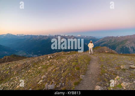 Frau beobachten, atemberaubenden Sonnenaufgang über Täler, Grate und Gipfel. Mont Blanc, Valle d'Aosta. Sommer Abenteuer auf der italienischen Alpen. Stockfoto