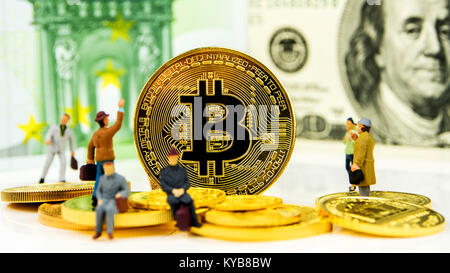 Nahaufnahme des Goldenen bitcoin Münze auf Dollar banknote Hintergrund mit vielen goldenen Münzen unten und minifigürchen herum Stockfoto