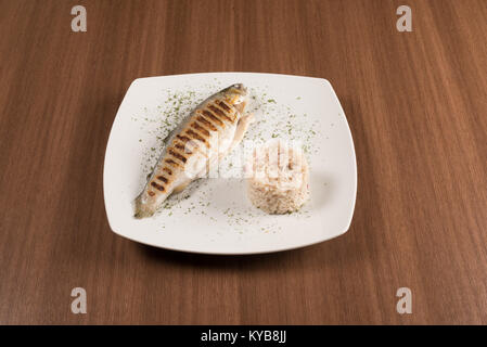 Gegrillte Forelle mit Reis auf einem mit Teller Stockfoto