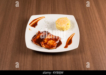 Schweinekoteletts mit roten Würsten und Reis auf einem weißen Teller Stockfoto