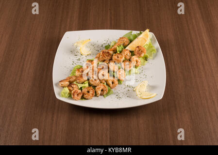 Garnelen mit Salat und Zitronen auf weißem Hintergrund Stockfoto