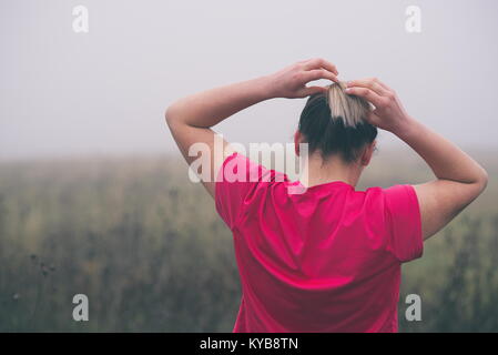 Junge Frau zur Festsetzung Haar draußen vor der Ausführung Stockfoto