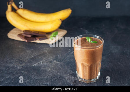 Glas Obst Banane - Schokolade Smoothie mit Minze und ingridients auf dem dunklen Hintergrund. Gesunde, vegetarische, vegane Diät essen. Selektive Schwerpunkte Stockfoto