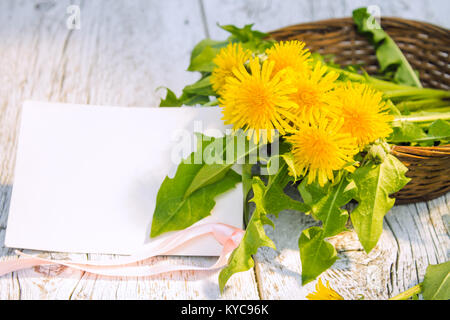 Strauß gelber Löwenzahn Blumen in einem Korb closeup auf einem weißen Holz- Hintergrund. Flache Tiefenschärfe, Fokus auf Blumen Stockfoto