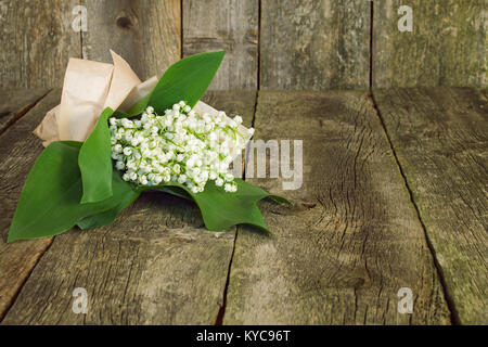 Blumenstrauß aus Lilien auf das Tal in einem Papier verpacken auf alten hölzernen Hintergrund Stockfoto