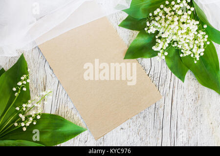 Blumenstrauß aus Lilien auf das Tal mit einem Schleier auf einem alten weißen Holz- Hintergrund mit einem leeren Blatt Papier Stockfoto