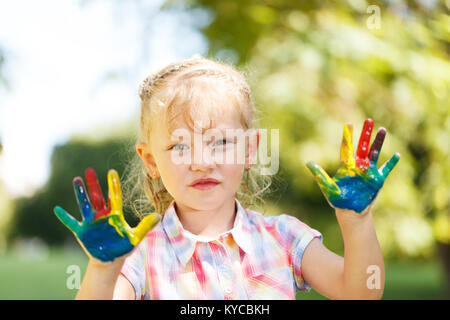 Vier Jahre altes Mädchen mit Händen in bunten Farben bereit für Hand druckt lackiert Stockfoto