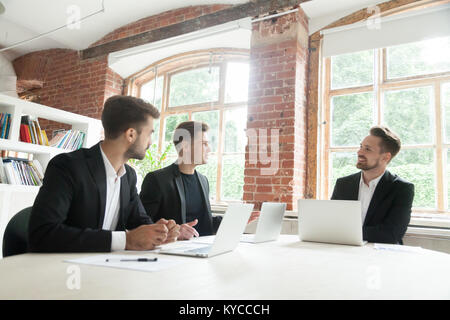 Drei Unternehmer in Anzügen verhandeln diskutieren auf Konferenz Büro Tisch sitzen, bei der Sitzung des Verwaltungsrates der Planung neuer Vorhaben, Par Stockfoto