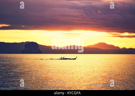 Erstaunlich Sonnenaufgang auf dem Meer. Silhouette eines kleinen Fischerboot gegen tropische Inseln zwischen Phuket und Krabi in Thailand. Stockfoto