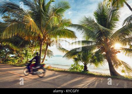 Touristische fährt Motorrad auf der tropischen Insel im Sunrise. Koh Yao Noi, Thailand Stockfoto