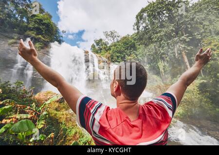 Glücklich, junger Mann (Reisenden) in der Nähe von Wachirathan Wasserfälle im tropischen Regenwald. Provinz Chiang Mai, Thailand Stockfoto