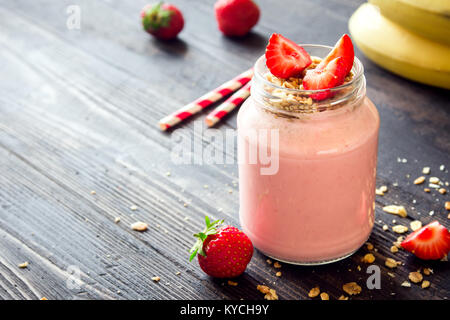 Erdbeeren und Bananen Smoothie mit hausgemachtem Müsli. Gesundes Frühstück oder einen Snack. Banane und Erdbeere Smoothie in Glas. Stockfoto