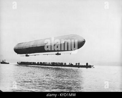 Ein Foto von Peter Scherer, das ein zeppelin-Luftschiff zeigt, das über den Bodensee in Deutschland fliegt und die frühe Luftfahrt und die malerische Luftaufnahme des Sees und des umliegenden Geländes einfängt. Stockfoto